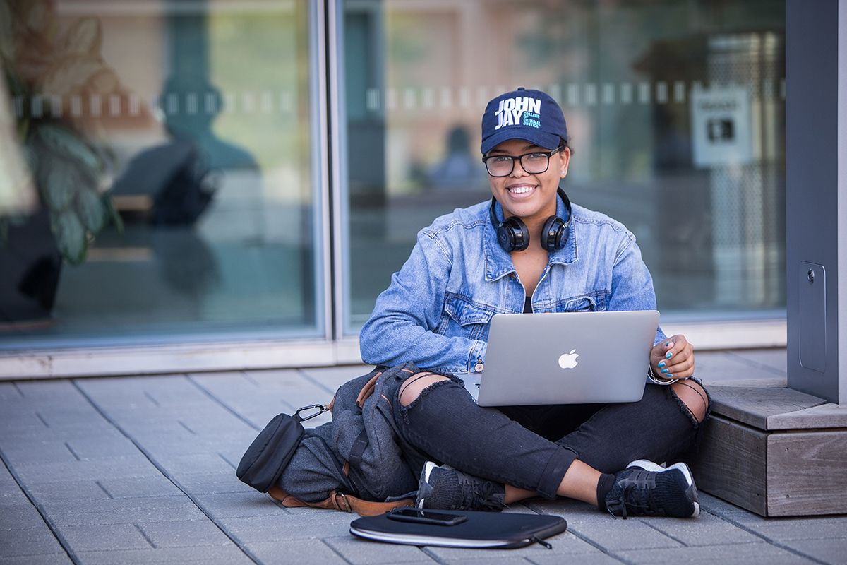 John Jay Student sitting and working on laptop