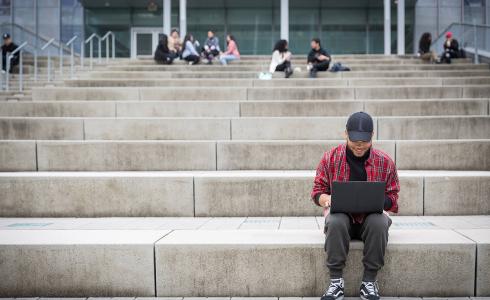 Student sitting on steps working on laptop