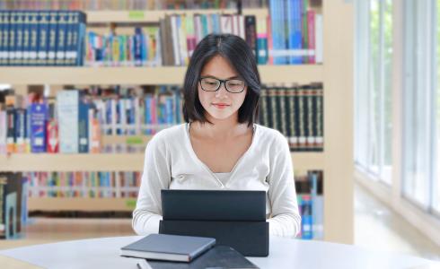 student with laptop in library